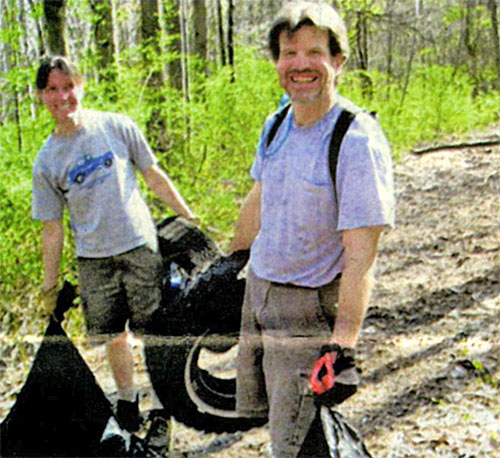 Mindy Heller and Butch Bittner remove a bag of garbage and one of many tires found in the park.